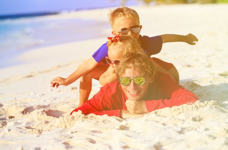 happy father with two kids having fun on sand tropical beachの写真素材