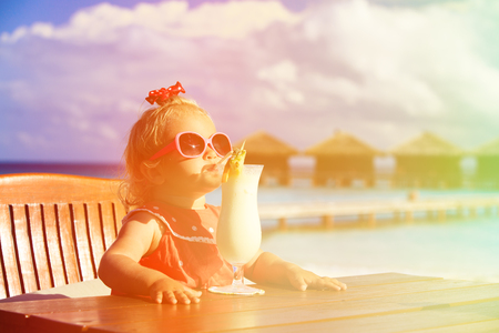 cute little girl drinking cocktail on tropical beach resortの写真素材