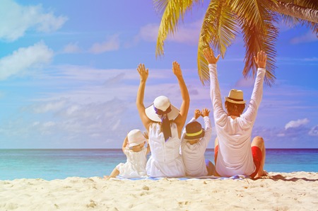 happy family with two kids hands up on the beachの写真素材