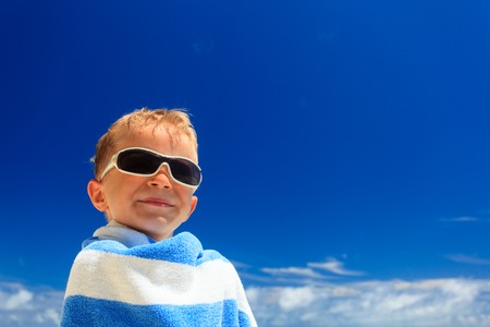 happy little boy laugh wrapped in beach towel on skyの写真素材