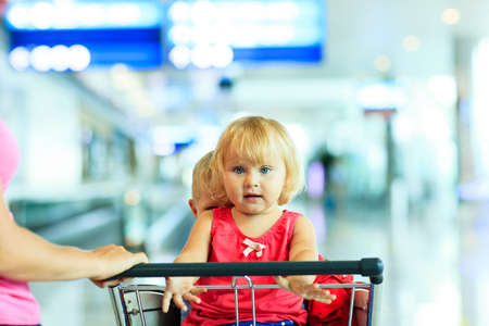 mother and two kids on luggage cart in the airportの写真素材