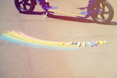 child's drawing of rainbow and colorful chalks on a streetの写真素材