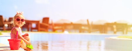 cute little girl playing in swimming pool at tropical beach, panoramaの写真素材