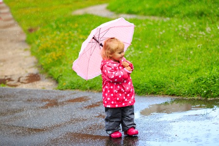 cute little girl having fun on rain, kids play outdoorsの写真素材
