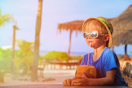 little boy drinking coconut cocktail on tropical beachの写真素材