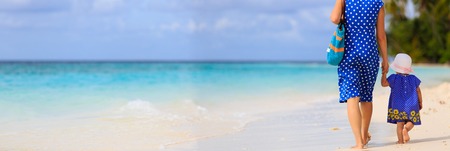 rear view of mother and little daughter walking on tropical beach, panoramaの写真素材