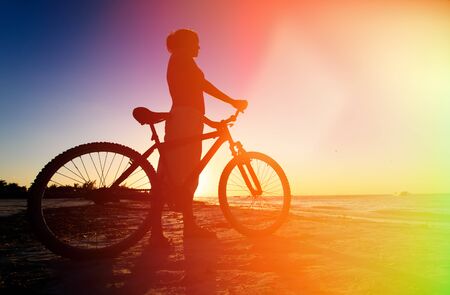 silhouette of woman biking at sunset beachの写真素材