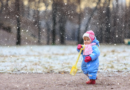 little girl making first steps in snow winter parkの写真素材