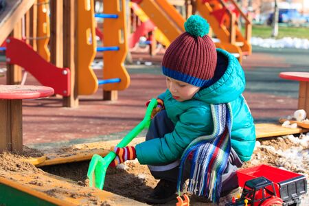 little boy digging in playground , winter kids activitiesの写真素材