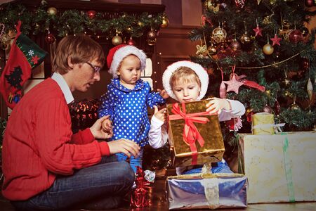 father and kids with presents in christmas home
