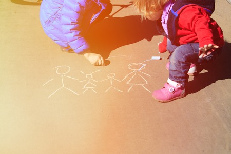 little boy and girl drawing family with chalk on asphalt, kids outdoor activitiesの写真素材