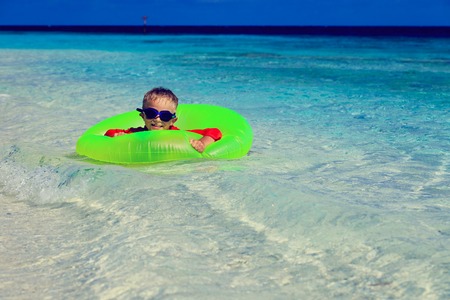 happy little boy with life ring having fun on tropical beachの写真素材