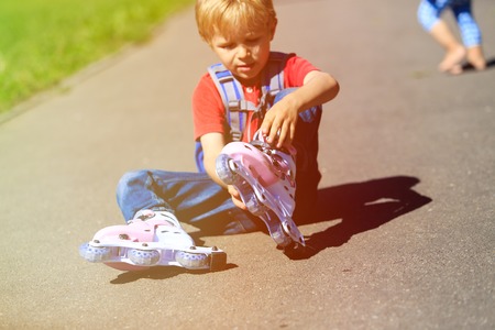 cute little boy put on roller skates outdoorsの写真素材