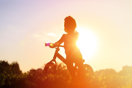little girl riding bike at sunset, active kids sportの写真素材