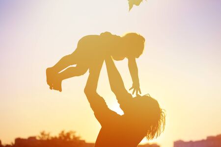 silhouettes of father and little daughter playing at sunset skyの写真素材