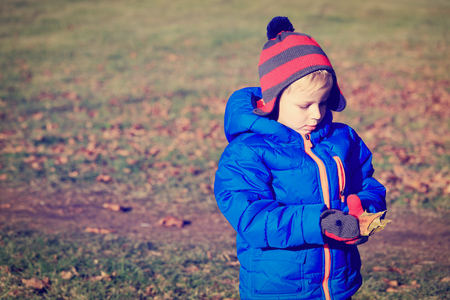 little boy playing with leaves in autumnの写真素材
