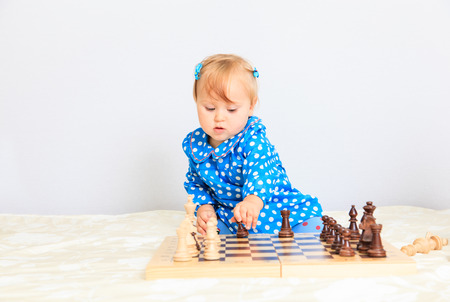 cute little girl playing chess indoors, early learningの写真素材