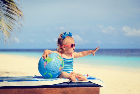 little girl with globe and toy plane on beach, kids travelの写真素材