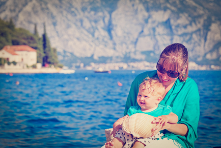 mother and little daughter playing with seashell on vacationの写真素材