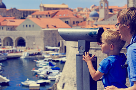 father and son looking through binoculars at the city of Dubrovnikの写真素材