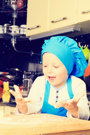 happy little boy kneading dough in kitchenの写真素材