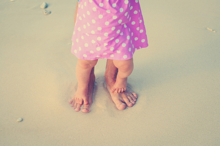 Close up of father and little daughter feet on a tropical beachの写真素材