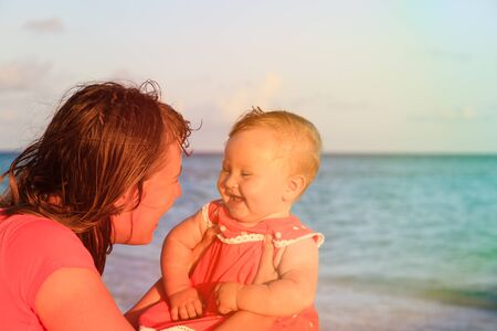 mother and little daughter having fun at sunset tropical beachの写真素材