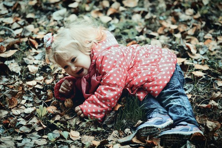 crying child in autumn leaves, autumn depression and sadnessの写真素材