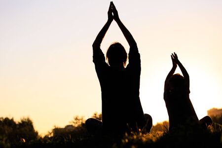 father and son doing yoga at sunset sky, active familyの写真素材