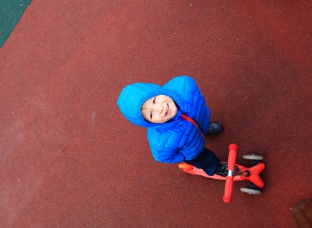 cute little boy riding scooter, high angle viewの写真素材