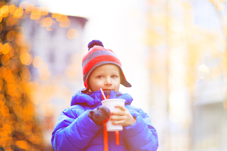 little boy having hot drink in cold winter christmas cityの写真素材