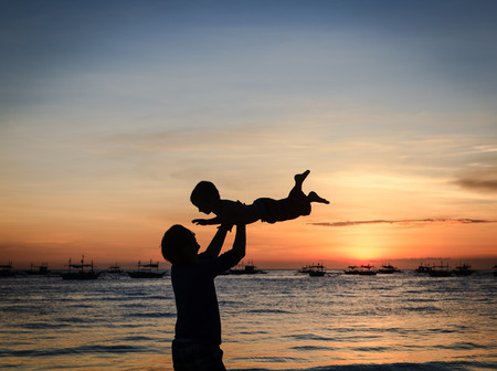 father and son playing at sunset seaの写真素材