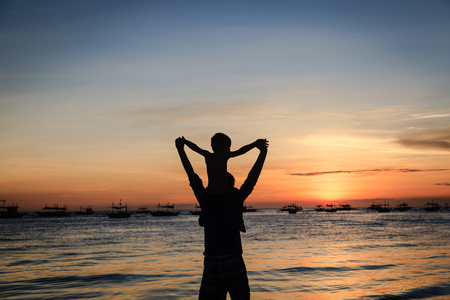 father and son on sky at sunset beachの写真素材