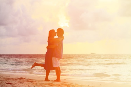 Happy young romantic couple on the beach at sunsetの写真素材
