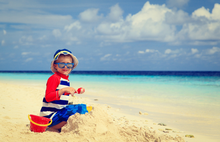 little boy building sandcastle on tropical sand beachの写真素材