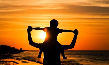 father and son having fun on sunset beachの写真素材