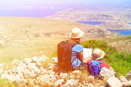 mother and son looking at map in mountains, family travel
