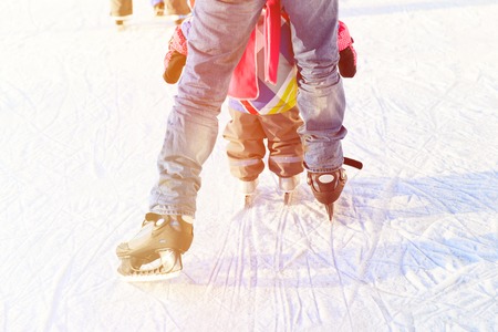father and little daughter feet learning to skate in winter snowの写真素材