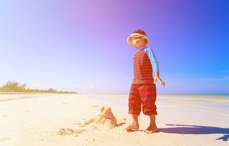 little boy building sandcastle on tropical sand beachの写真素材