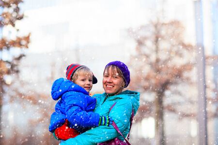 mother and son enjoy first snow, family winter in the cityの写真素材