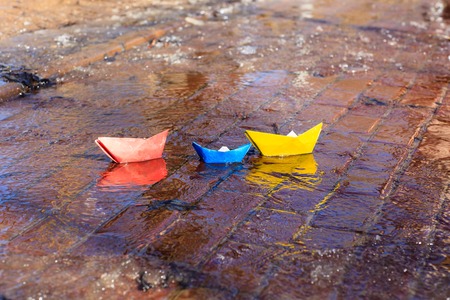 paper boats in spring water puddle, kids play in springの写真素材