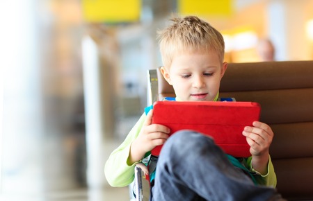 little boy looking at touch pad while travel in the airportの写真素材