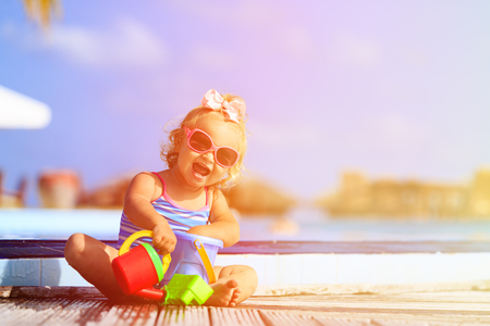 cute little girl playing in swimming pool at tropical beachの写真素材