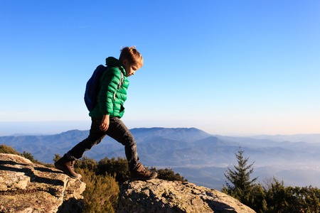 little boy with backpack hiking in scenic mountains, kids travel