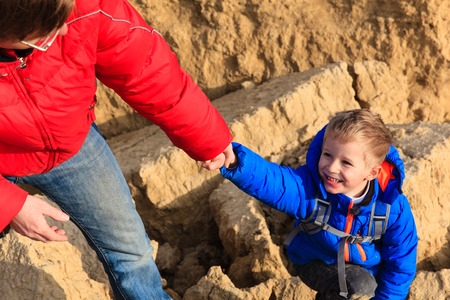Helping hand- little boy helped by parent on hiking in mountains