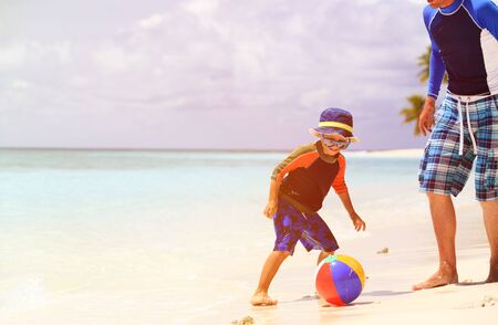 father and son playing ball at beach, family beach activitiesの写真素材