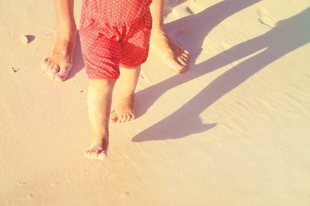 Mother and baby feet walking on sand beach, kids learningの写真素材