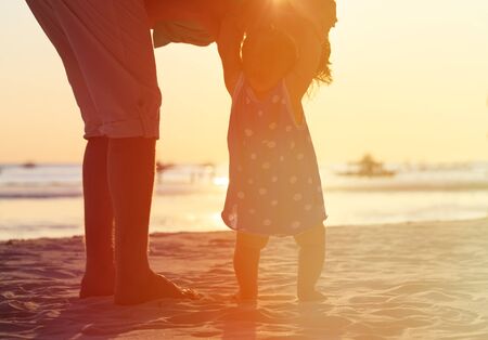 Silhouette of father and little daughter walk at sunset beachの写真素材
