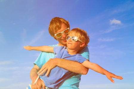 Father and little son playing on blue summer sky