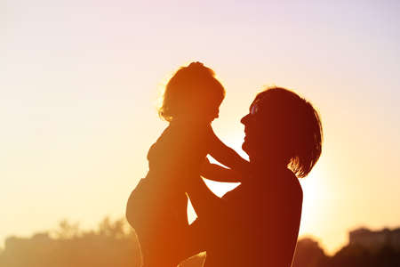 silhouettes of father and little daughter playing at sunsetの写真素材